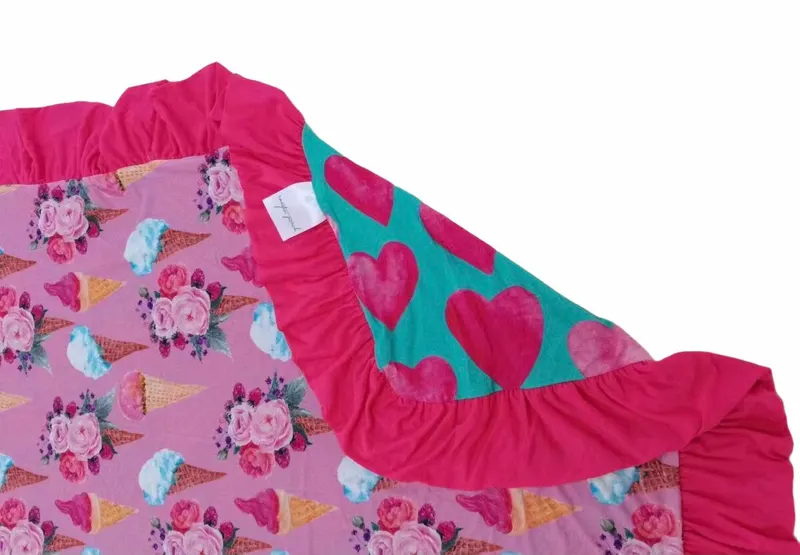 Reversible bamboo blanket showing ice cream floral print and pink hearts print with ruffle border