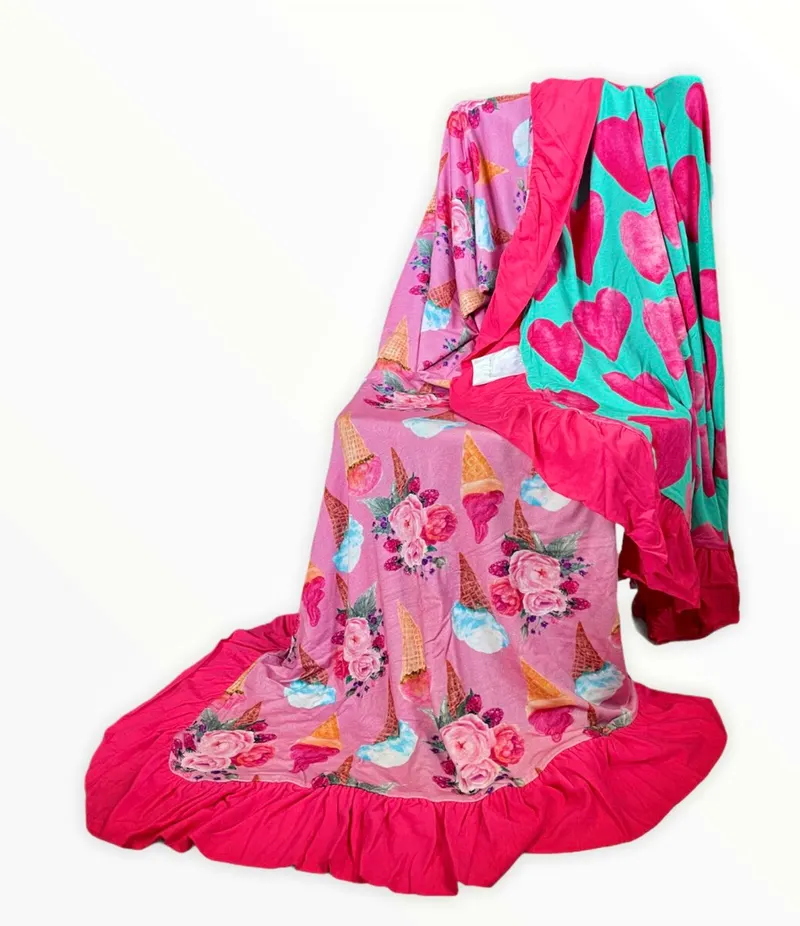 Reversible bamboo blanket showing ice cream floral print and pink hearts print with ruffle border