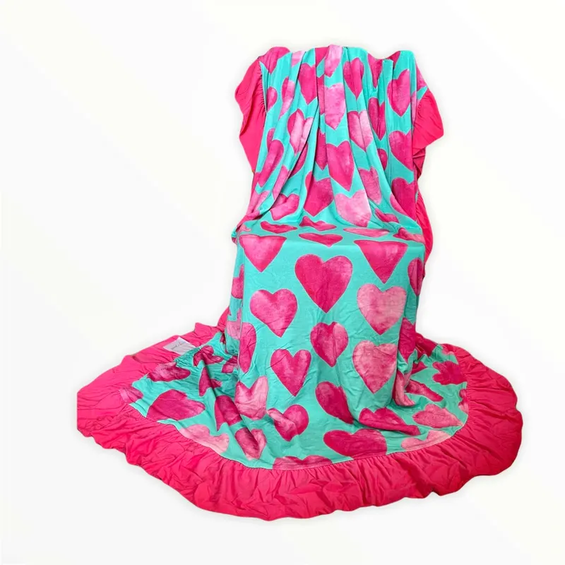 Reversible bamboo blanket showing ice cream floral print and pink hearts print with ruffle border