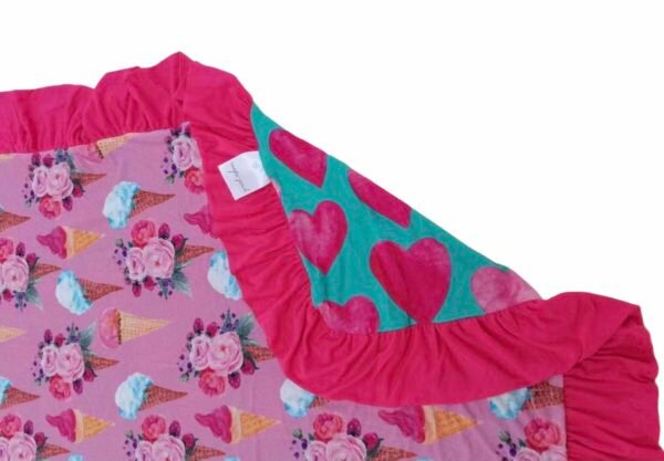 Reversible bamboo blanket showing ice cream floral print and pink hearts print with ruffle border